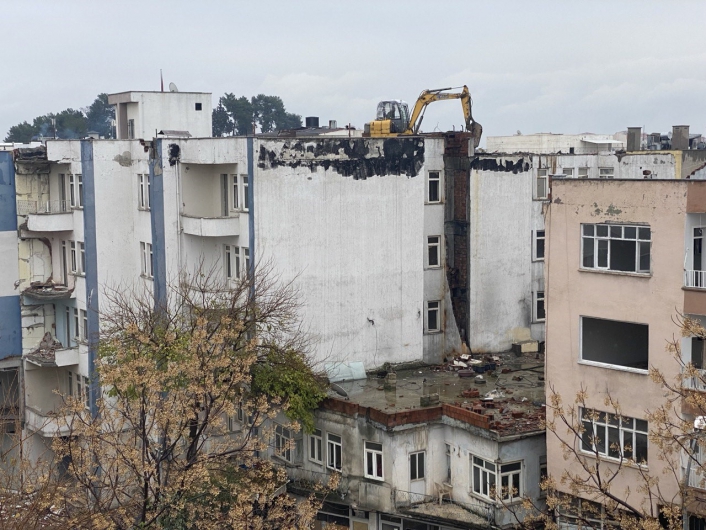 İş makinası yıkım için ağır hasarlı binanın üzerine çıkarıldı
